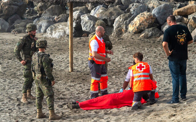 Spanish army soldiers and Red Cross workers assist a migrant who swam from Morocco to the Spanish enclave of Ceuta, August 1, 2026. (AP Photo/Antonio Sempere)