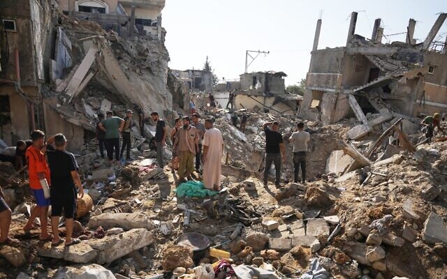 Palestinians inspect destroyed buildings at the scene of an Israeli airstrike, at al-Maghazi refugee camp, central Gaza Strip, August 1, 2026. (AP/Abdel Kareem Hana)