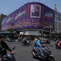 Vehicles drive past a billboard showing a photo of the late Iranian Supreme Leader Ayatollah Ali Khamenei, right, greeting the late Hamas leader Ismail Haniyeh, and Iranian and Palestinian flags, at an intersection in downtown Tehran, Iran, August 1, 2026. (AP/Vahid Salemi)