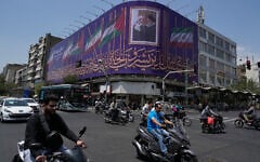 Vehicles drive past a billboard showing a photo of the late Iranian Supreme Leader Ayatollah Ali Khamenei, right, greeting the late Hamas leader Ismail Haniyeh, and Iranian and Palestinian flags, at an intersection in downtown Tehran, Iran, August 1, 2026. (AP/Vahid Salemi)