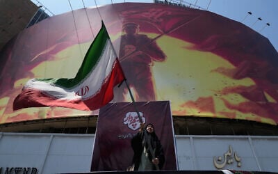 A woman waves an Iranian flag next to a billboard showing a graphic of a man wearing a shirt showing the face of late Iranian supreme leader Ayatollah Ali Khamenei with words calling upon the avengers of Imam Hussein, in a square in downtown Tehran, Iran, August 1, 2026. (AP Photo/Vahid Salemi) A woman waves an Iranian flag next to a billboard showing a graphic of a man wearing a shirt showing the face of late Iranian supreme leader Ayatollah Ali Khamenei with words calling upon the avengers of Imam Hussein, in a square in downtown Tehran, Iran, August 1, 2026. (AP Photo/Vahid Salemi)