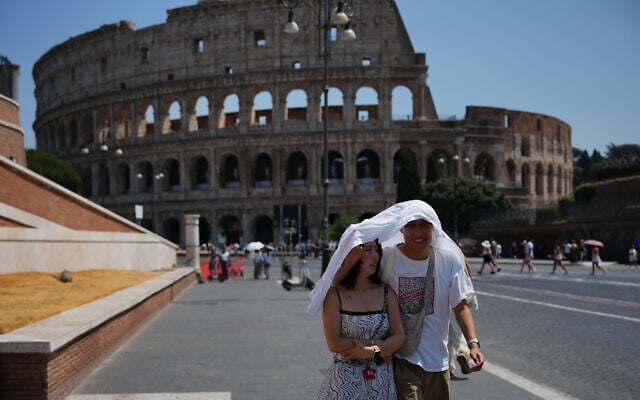 Tourists take shelter as they walk in front of Rome’s ancient Colosseum, August 1, 2026. (AP Photo/Alessandra Tarantino)