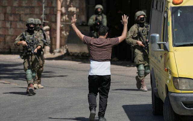 A Palestinian man walks toward Israeli soldiers with his hands raised during an Israeli military operation in the West Bank city of Nablus, August 2, 2026. (AP/Majdi Mohammed)