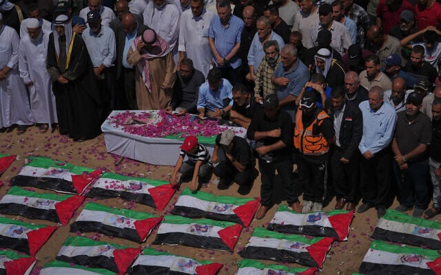 Mourners gather around the flag-draped bodies of members of the Hassayna and Abu Sharia families, allegedly killed in an Israeli strike in 2023 and recently recovered from the rubble, during their funeral in Gaza City, August 4, 2026. (AP Photo/Jehad Alshrafi)