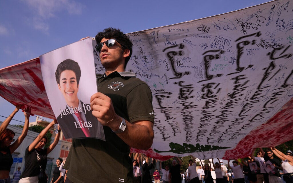 Relatives of victims of the 2020 Beirut port explosion, hold a giant Lebanese flag and portraits of their loved ones as they march during a memorial ceremony marking the sixth anniversary of the massive blast in Beirut, Lebanon, August 4, 2026. (AP Photo/Hussein Malla)