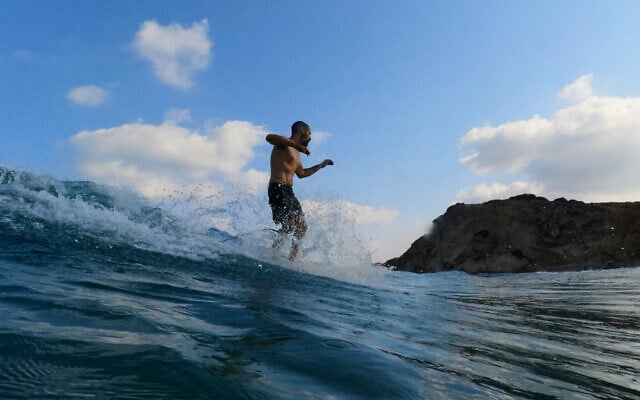 Erez Gomel surfs in the Mediterranean Sea in Gador Sea and Nature Reserve in Hadera, Israel, during a heat wave on August 5, 2026. (AP Photo/Ariel Schalit)
