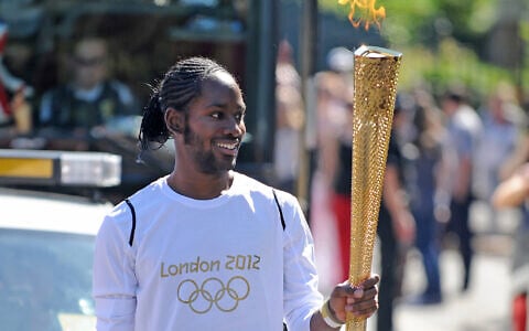 Torchbearer Jason Arday carries the Olympic Flame on the Torch Relay leg between Sutton and Merton, in London, July 23, 2012. (Joe Giddens/LOCOG/PA via AP)