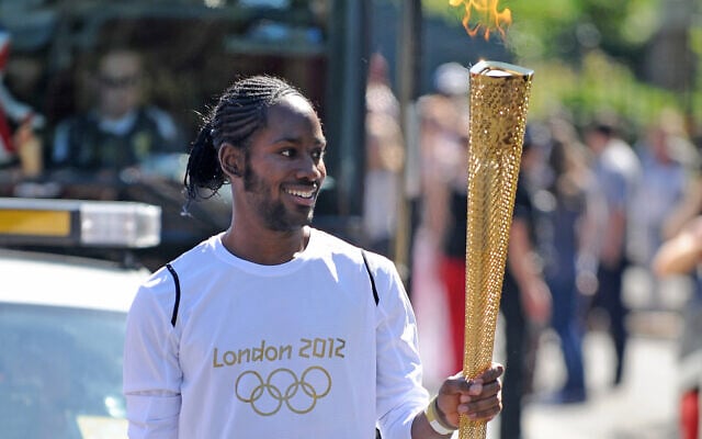 Torchbearer Jason Arday carries the Olympic Flame on the Torch Relay leg between Sutton and Merton, in London, July 23, 2012. (Joe Giddens/LOCOG/PA via AP)