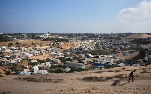 A Palestinian man pulls an empty cart past a sprawling makeshift camp for displaced people in Deir al-Balah, central Gaza Strip, August 7, 2026. (AP Photo/Abdel Kareem Hana)
