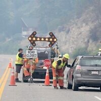 Emergency crews talk to the driver of a car at a closed section of Highway 97 south of Peachland, British Columbia, Canada, on August 8, 2026. (Gary Nylander/The Canadian Press via AP)
