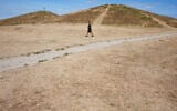 A man walks on dried grass in a park, amid drought conditions in London, in London, August 9, 2026. (AP Photo/Kirsty Wigglesworth)