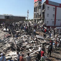 Residents and rescue workers search through the rubble of a collapsed building after an earthquake struck Cali, Colombia, August 10, 2026. (AP Photo/ Santiago Saldarriaga)