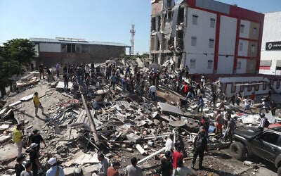 Residents and rescue workers search through the rubble of a collapsed building after an earthquake struck Cali, Colombia, August 10, 2026. (AP Photo/ Santiago Saldarriaga)