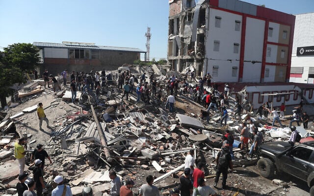 Residents and rescue workers search through the rubble of a collapsed building after an earthquake struck Cali, Colombia, August 10, 2026. (AP Photo/ Santiago Saldarriaga)