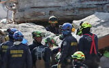 Rescue workers search through the rubble of a collapsed building the day after an earthquake struck Cali, Colombia, August 11, 2026. (AP Photo/Santiago Saldarriaga)