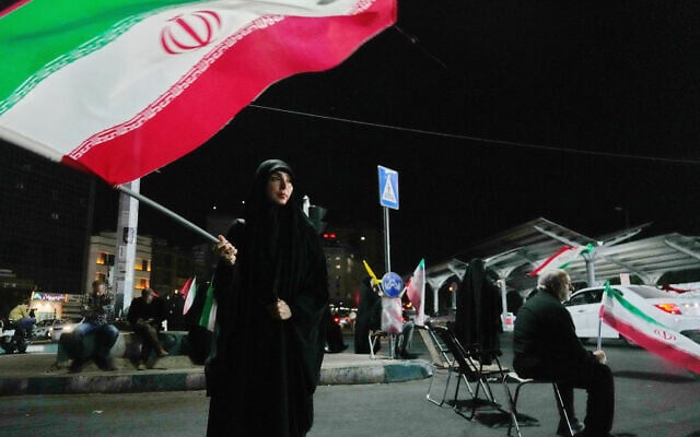 A woman waves an Iranian flag during a pro-government gathering at a square in Tehran, Iran, August 11, 2026. (AP Photo/Vahid Salemi)