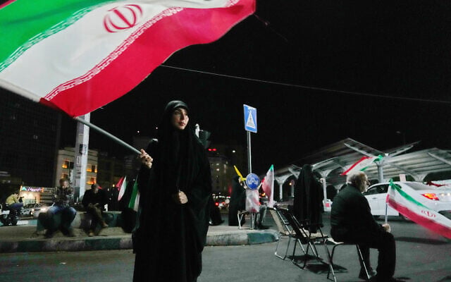 A woman waves an Iranian flag during a pro-government gathering at a square in Tehran, Iran, August 11, 2026. (AP Photo/Vahid Salemi)