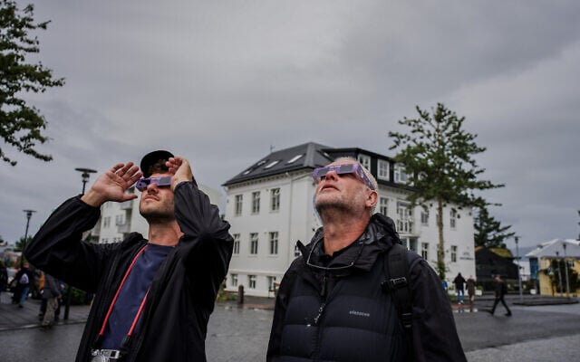 People use solar eclipse glasses to look up at the sun ahead of a solar eclipse Reykjavik, Iceland, August 12, 2026. (AP Photo/Marco di Marco)