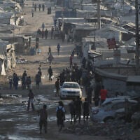 Palestinians walk among tents and rubble on the coastal road in Gaza City, in the Strip's north, on August 13, 2026. (AP Photo/Abdel Kareem Hana)
