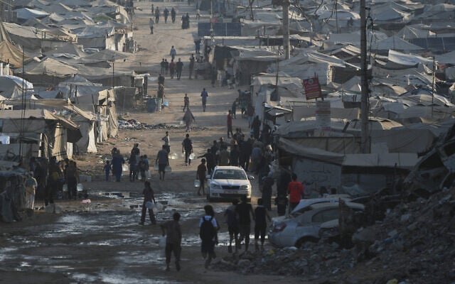 Palestinians walk among tents and rubble on the coastal road in Gaza City, in the Strip's north, on August 13, 2026. (AP Photo/Abdel Kareem Hana)