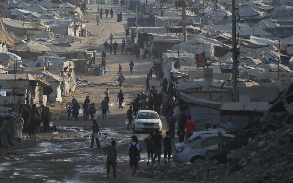 Palestinians walk among tents and the rubble of buildings destroyed during the Israel-Hamas war along the coastal road in Gaza City, August 13, 2026. (AP Photo/Abdel Kareem Hana)