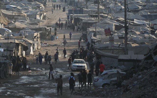 Palestinians walk among tents and the rubble of buildings destroyed during the Israel-Hamas war along the coastal road in Gaza City, August 13, 2026. (AP Photo/Abdel Kareem Hana)