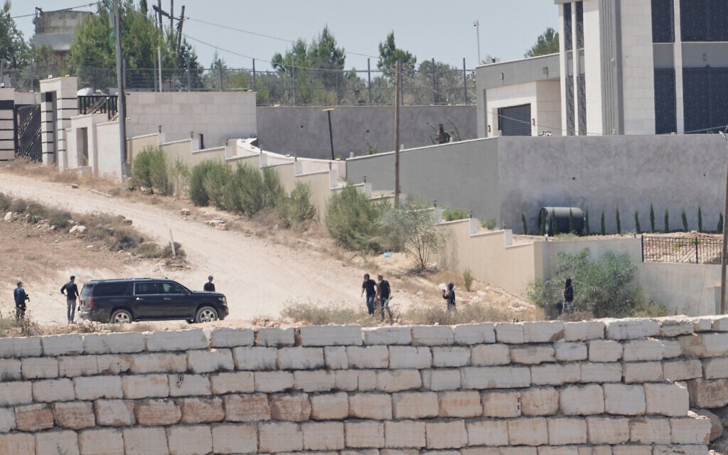 Israeli settlers gather in front of Palestinian houses they are besieging in the West Bank village of Qusra, south of Nablus, August 13, 2026. (AP Photo/Majdi Mohammed)