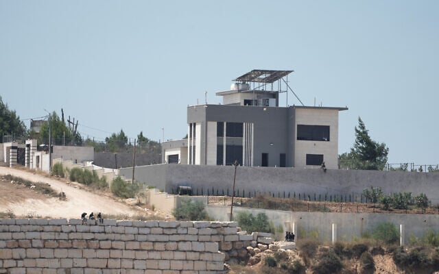 Israeli settlers gather in front of Palestinian houses they are besieging in the West Bank village of Qusra, south of Nablus, August 13, 2026. (AP/Majdi Mohammed)