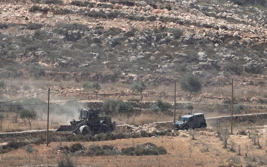 Israeli army vehicles operate near Palestinian houses, besieged by Israeli settlers, in the West Bank village of Qusra, south of Nablus, August 13, 2026. (AP Photo/Majdi Mohammed)