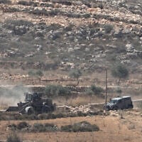 Israeli army vehicles operate near Palestinian houses, besieged by Israeli settlers, in the West Bank village of Qusra, south of Nablus, August 13, 2026. (AP Photo/Majdi Mohammed)