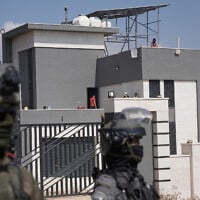 Israeli forces stand in front of the entrance of a Palestinian house besieged by Israeli settlers in the village of Qusra, south of Nablus, in the West Bank, on August 14, 2026. (AP Photo/Majdi Mohammed)