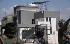 Israeli forces stand in front of the entrance of a Palestinian house besieged by Israeli settlers in the village of Qusra, south of Nablus, in the West Bank, on August 14, 2026. (AP Photo/Majdi Mohammed)