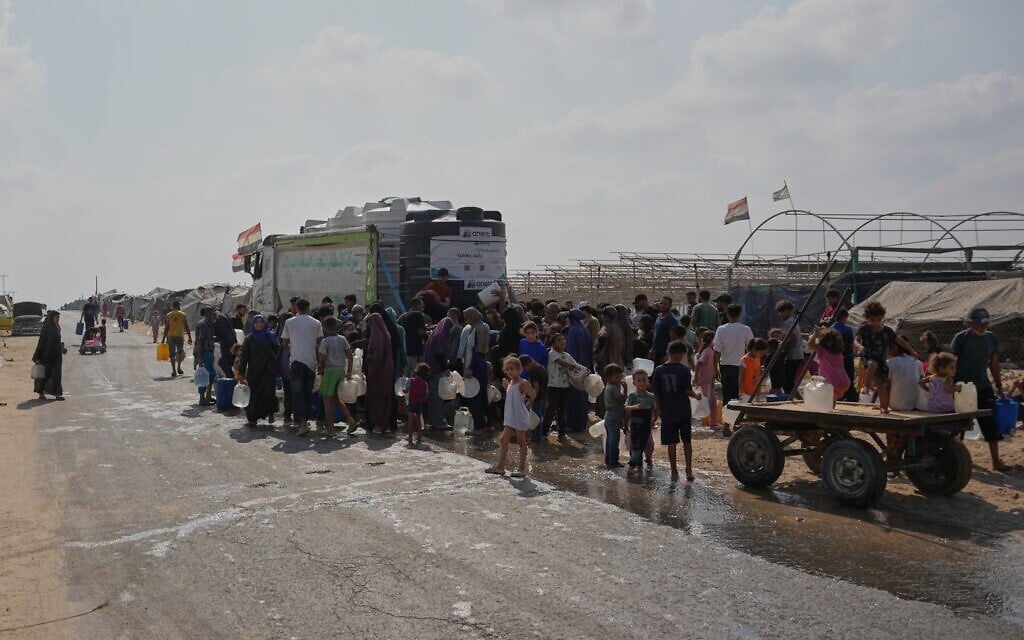 Displaced Palestinians gather to refill fresh water by a water supplier in Deir al-Balah, central Gaza Strip, Aug 14, 2026. (AP/Abdel Kareem Hana)