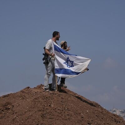 Israeli settlers put up an Israeli flag on a hilltop after it was taken down by Israeli and foreign peace activists during a protest in support of local landowners whose property is threatened with seizure by settlers, on the outskirts of the West Bank city of Beit Sahour, August 14, 2026. (AP Photo/Mahmoud Illean)