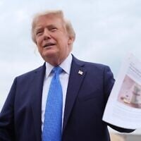US President Donald Trump holds an article about prescription drug prices as he speaks with reporters before boarding Air Force One, August 14, 2026, at Joint Base Andrews, Md. (AP Photo/Julia Demaree Nikhinson)