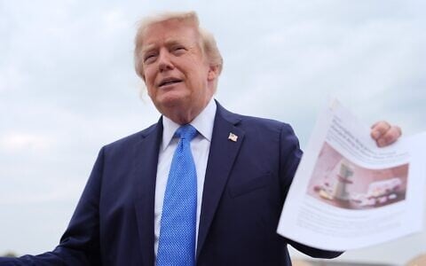 US President Donald Trump holds an article about prescription drug prices as he speaks with reporters before boarding Air Force One, August 14, 2026, at Joint Base Andrews, Md. (AP Photo/Julia Demaree Nikhinson)