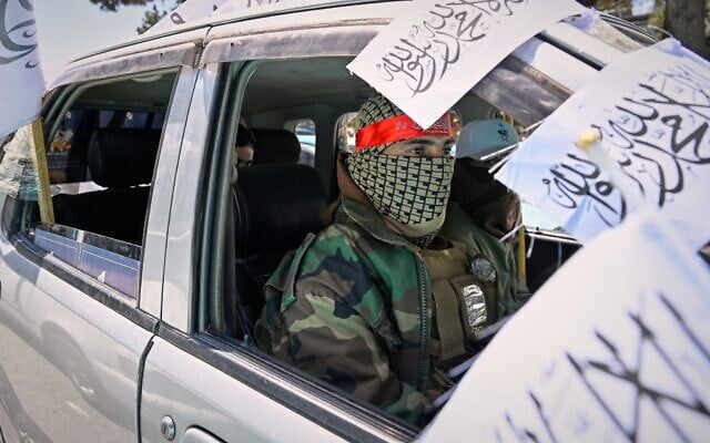 A masked Taliban operative rides in a vehicle decorated with Taliban flags during celebrations marking the fifth anniversary of the US withdrawal from Afghanistan and the Taliban’s return to power, in Kabul, Afghanistan, August 15, 2026. (AP Photo/Nava Jamshidi)