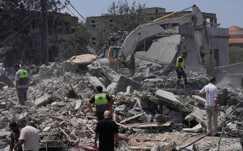Rescue workers gather on a destroyed building that was hit by an Israeli airstrike in Deir al-Zahrani village, southern Lebanon, August 15, 2026. (AP Photo/Mohammed Zaatari)