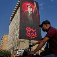 A man rides on his motorbike past a billboard with a message that reads in Farsi: 'We must rise up' and an image of the late Iranian supreme leader ayatollah Ali Khamenei, in Tehran, Iran, August 15, 2026. (AP/Vahid Salemi)