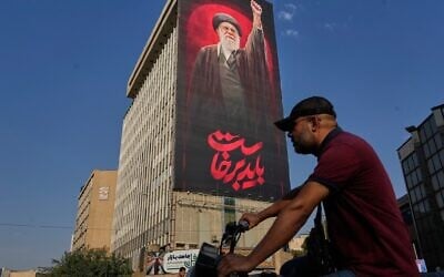 A man rides on his motorbike past a billboard with a message that reads in Farsi: 'We must rise up' and an image of the late Iranian supreme leader ayatollah Ali Khamenei, in Tehran, Iran, August 15, 2026. (AP/Vahid Salemi) A man rides on his motorbike past a billboard with a message that reads in Farsi: 'We must rise up' and an image of the late Iranian supreme leader ayatollah Ali Khamenei, in Tehran, Iran, August 15, 2026. (AP/Vahid Salemi)