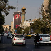 A billboard with a message that reads in Persian: 'We must rise up' and an image of the late Iranian Supreme Leader Ayatollah Ali Khamenei towers over downtown traffic in Tehran, Iran, August 15, 2026. (AP Photo/Vahid Salemi)