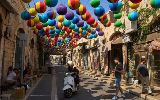 People walk beneath an art installation of colorful spheres along a pedestrian street in Jaffa, August 16, 2026. (AP/Oded Balilty)
