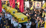 Hezbollah scouts carry the coffins of a Hezbollah member Ali al-Haj Hassan, his wife and his four children, who were killed on Saturday by an Israeli airstrike, during their funeral procession in the southern suburb of Beirut, Lebanon, August 16, 2026. (AP Photo/Hussein Malla)