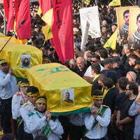 Hezbollah scouts carry the coffins of a Hezbollah member Ali al-Haj Hassan, his wife and his four children, who were killed on Saturday by an Israeli airstrike, during their funeral procession in the southern suburb of Beirut, Lebanon, August 16, 2026. (AP Photo/Hussein Malla)