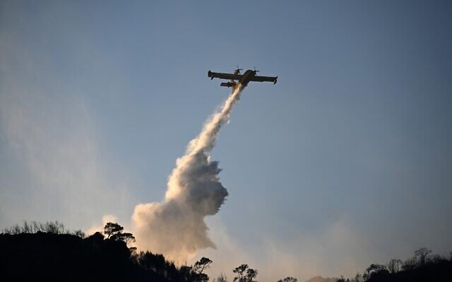 A firefighting airplane drop water during a wildfire on the island of Salamina, west of Athens, Greece, August 16, 2026. (AP Photo/Michael Varaklas)