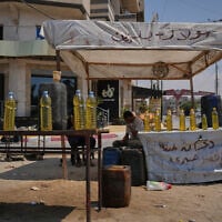 A Palestinian vendor offers bottles of diesel for sale in al-Maghazi refugee camp, central Gaza Strip, August 15, 2026. (AP Photo/Abdel Kareem Hana)