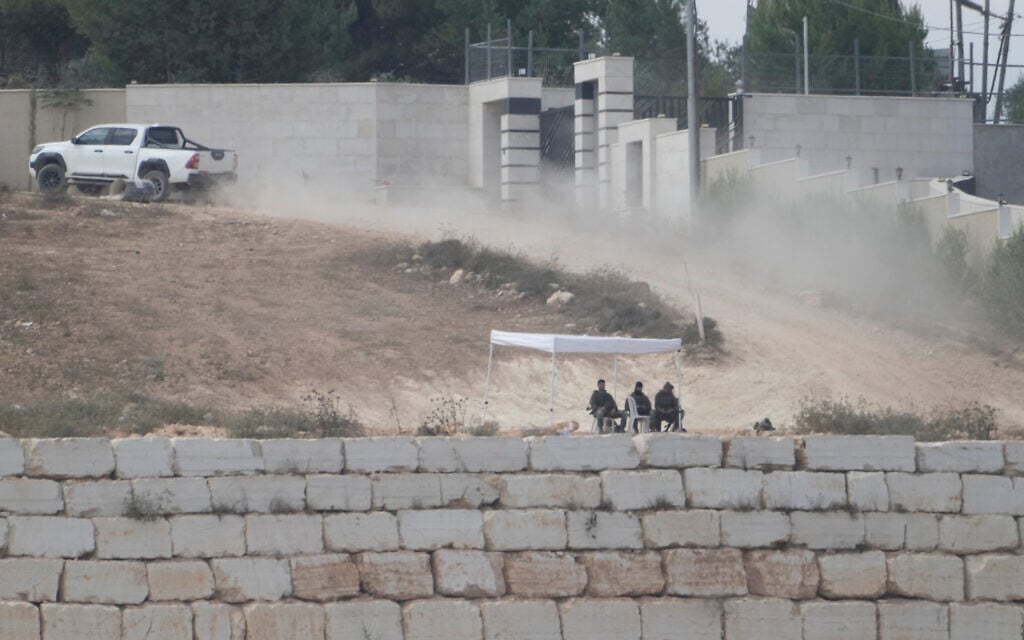IDF soldiers sit under a tent in front of the house of Ohio-based Palestinian-American landlord Loui Ridi, that has been besieged by extremist settlers for over a week, in the West Bank village of Qusra, south of Nablus, August 18, 2026. (AP Photo/Majdi Mohammed)