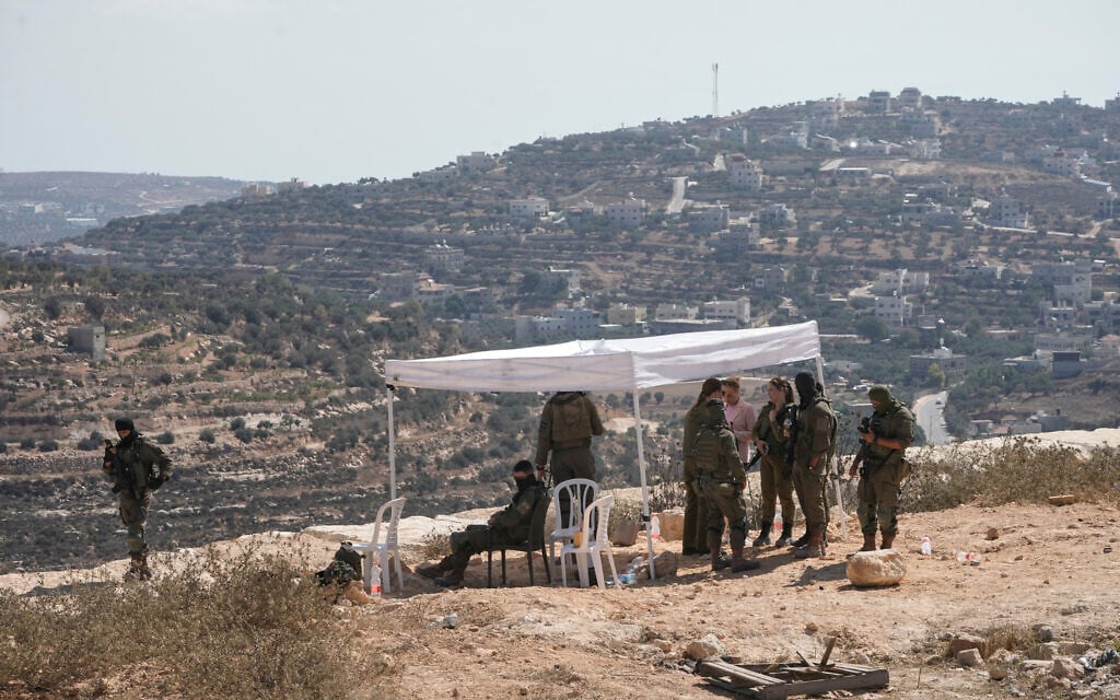 Israeli soldiers gather in front of the house of Palestinian-American landlord Louai Abu Ridi, which was besieged by Israeli settlers, in the West Bank village of Qusra, south of Nablus, August 19, 2026. (AP/Majdi Mohammed)