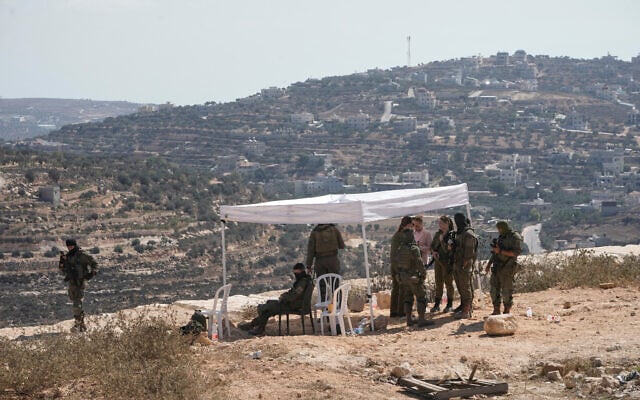 Israeli soldiers gather in front of the house of Palestinian-American landlord Loui Ridi, which was besieged by Israeli settlers, in the West Bank village of Qusra, south of Nablus, August 19, 2026. (AP/Majdi Mohammed)