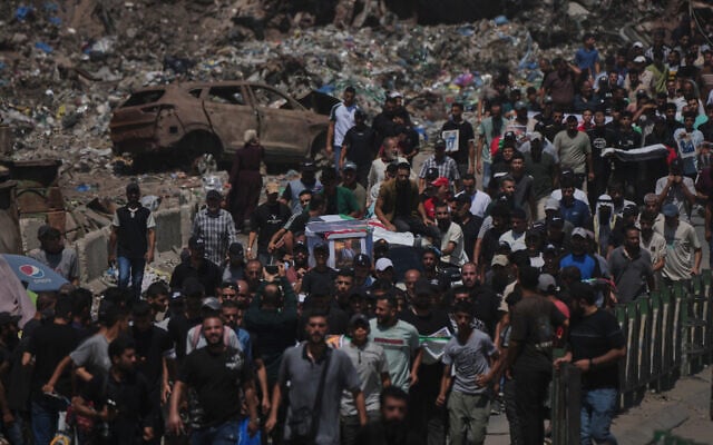 Mourners carry the flag-draped bodies of Palestinians killed in Israeli strikes during the war with Hamas, whose remains were recently recovered from the rubble, in Gaza City, August 20, 2026. (AP Photo/Jehad Alshrafi)